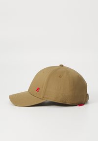 Khaki színű baseball sapka ívelt karimával, a frontján piros hímzett "R"-rel, és piros részlet a hátsó állítható pánton.