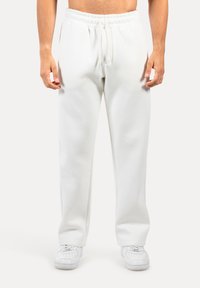 Weiße Sweatpants mit elastischem Bund und Kordelzug, aus weichem Stoff gefertigt. Verfügt über ein eng zulaufendes Bein und seitliche Schlitze für zusätzlichen Komfort.