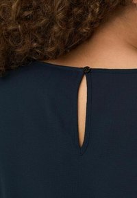 Námořnická blůza s klíčovou dírkou na zádech, zajištěná malým černým knoflíkem. Měkká látka a hladká textura.