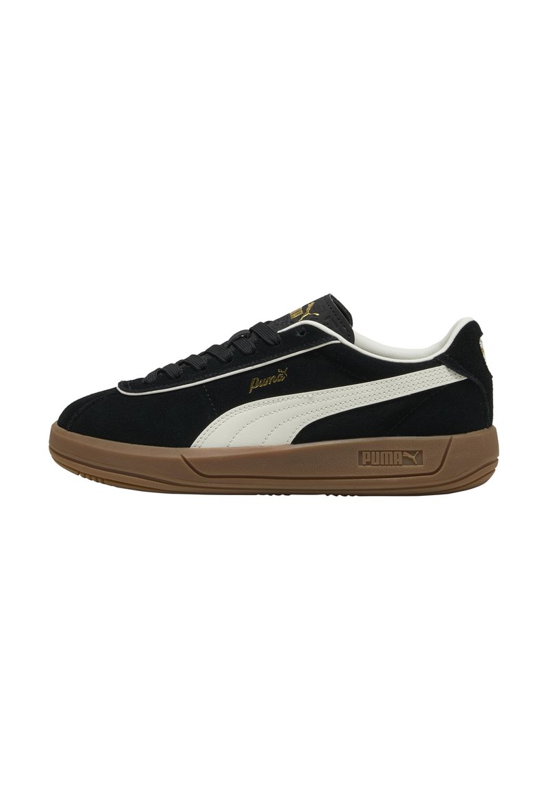 Zapatillas de ante negras con una franja lateral de cuero blanco y marca dorada, que cuentan con una suela de goma marrón y cordones negros.