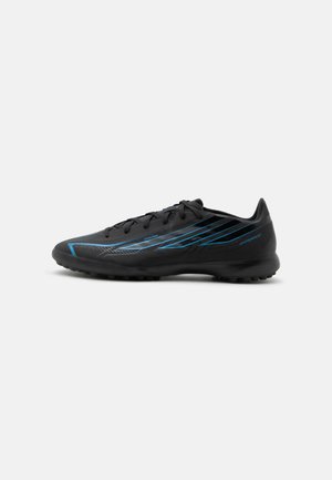 Μαύρο αθλητικό παπούτσι με μπλε γωνιώδεις λωρίδες, υφασμένο πέλμα για πρόσφυση και κλείσιμο με κορδόνια, φαίνεται σε προφίλ σε λευκό φόντο.