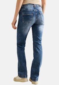 Bleka blå denimjeans med rak bendesign, tv�å bakfickor och subtila sömdetaljer. Bärs med beige sneakers.
