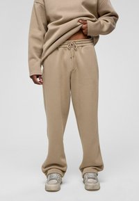 Beige, ontspannen-fit sweatpants met een elastische tailleband en verstelbaar trekkoord. Zachte stof met een gladde textuur en gestroomlijnd silhouet.