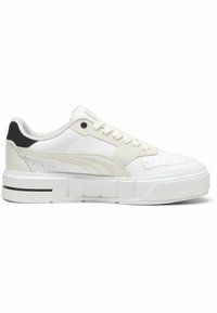Des baskets blanches avec un motif texturé, dotées d'une semelle blanche épaisse, de subtils accents beiges et d'un détail noir au talon. Les lacets sont entièrement blancs.