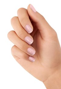Hand mit kurzen Nägeln, die mit einem hellrosa Nagellack in glatter Textur und subtiler glänzender Oberfläche lackiert sind. Die Fingernägel haben eine leichte weiße Spitze.