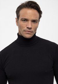 Zwarte turtleneck trui van ribbelstof, met een aansluitend ontwerp dat het bovenlichaam accentueert. Gladde textuur en strakke lijnen.