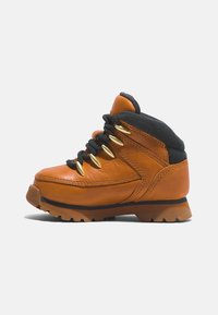 Bota de senderismo de cuero marrón con acentos negros, seis ojales dorados y suela resistente. Cuenta con un cuello acolchado y textura suave.
