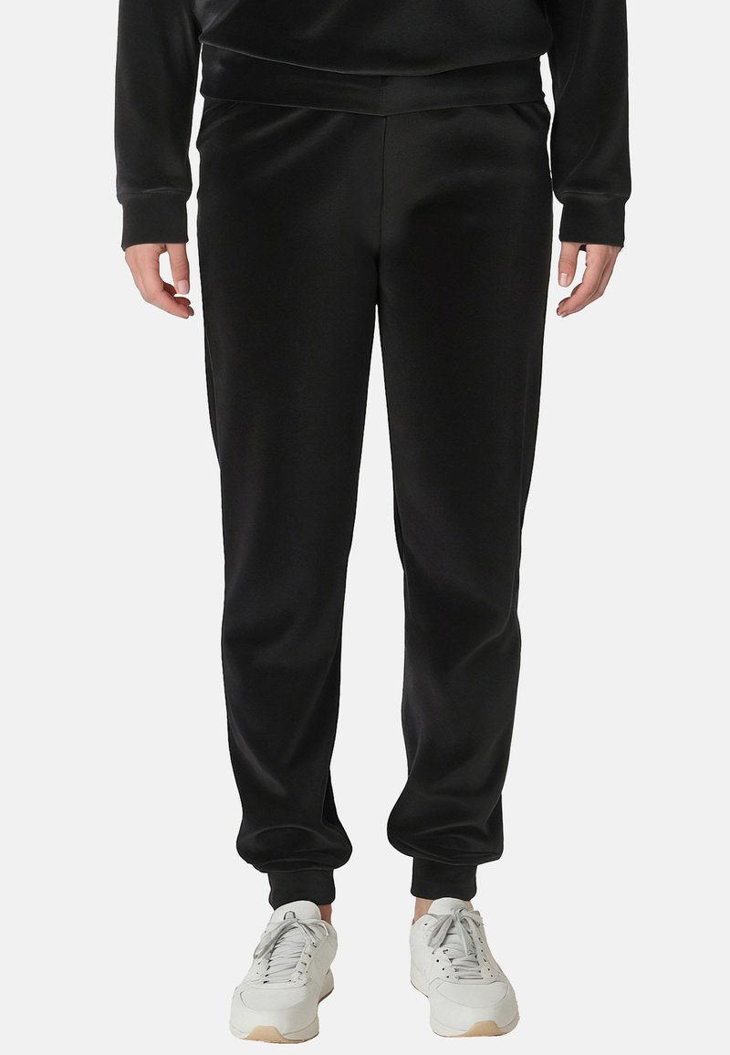 Svarte polyester-joggebukser med en glat tekstur, elastisk talje og smalle ben, parret med hvide sneakers. Ingen mønstre eller accenter synlige.