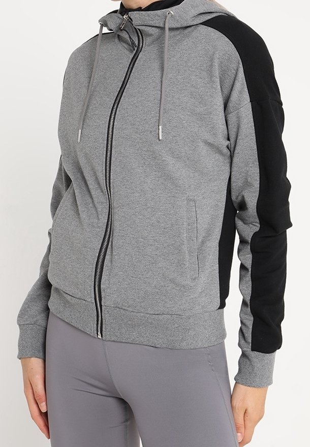 Haut à capuche zippé gris avec accents noirs, dotée d'une capuche à cordon de serrage, de poches latérales et de poignets côtelés, fabriquée en tissu doux en mélange de coton.