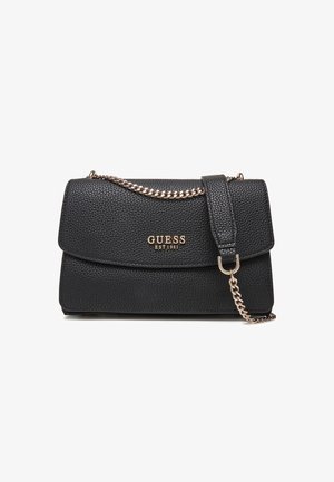 Schwarze, strukturierte Handtasche aus Kunstleder mit Klappenverschluss, goldfarbener Kettenriemen und auffälligem "GUESS EST.1981"-Logo auf der Vorderseite.