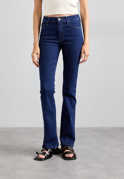 Jean évasé bleu marine en tissu denim, ajusté au niveau des cuisses, avec des coutures contrastées et une fermeture à bouton à la taille.