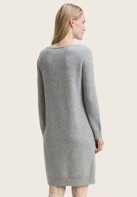 Robe pull grise à manches longues en texture tricotée douce, avec un col rond et des poignets et un ourlet côtelés.