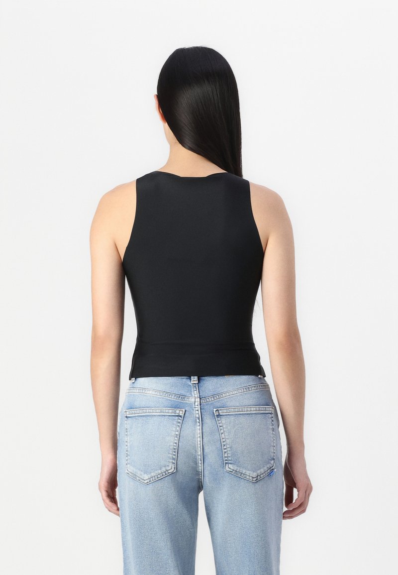 Schwarzes ärmelloses Oberteil mit rundem Halsausschnitt, taillierter Passform und glatter Textur. Kombiniert mit hellblauen Jeans mit Gesäßtaschen.