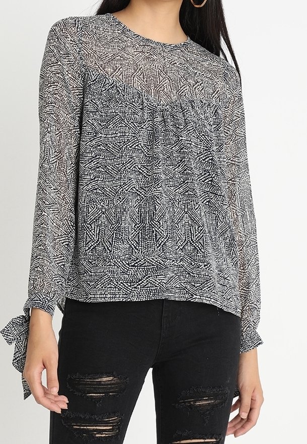 Blusa con collo rotondo e maniche lunghe, caratterizzata da un motivo geometrico bianco e nero e dettagli arricciati sotto il busto.