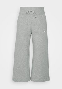 Grå vida sweatpants med dragsko i midjan, gjorda av mjukt tyg, med en vit Nike-logga på vänster sida.