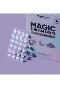 Patchs soin Magic Dream Dots en forme d’étoiles, de lunes et de nuages sur une feuille transparente à côté d’une boîte de produit lavande.