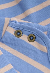 Close-up van blauw en beige gestreepte gebreide stof met twee metalen knopen genaaid aan een gevouwen rand.