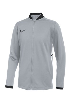 Hellgraue Nike-Jacke mit durchgehendem Reißverschluss, schwarzem Kragen, schwarzen Bündchen an den Handgelenken und schwarzem Nike-Swoosh-Logo auf der Brust.