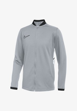 Hellgraue Nike-Jacke mit durchgehendem Reißverschluss, schwarzem Kragen, schwarzen Bündchen an den Handgelenken und schwarzem Nike-Swoosh-Logo auf der Brust.