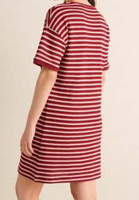 Rot-weißer gestreifter Strickkleid mit lockerer Passform, kurzen Ärmeln und rundem Ausschnitt. Der Stoff hat eine strukturierte Oberfläche.