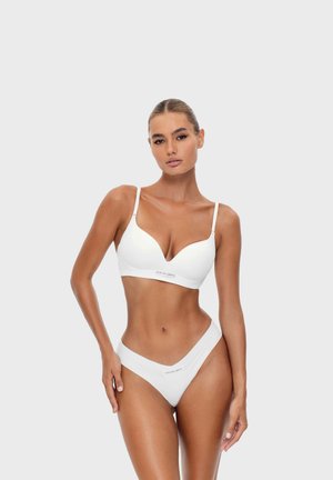 White seamless bra with a deep V-neckline and adjustable straps, paired with matching high-waisted thong featuring a logo detail.