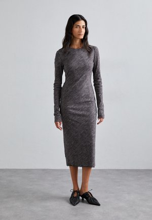 Long-sleeve, heather gray dress with a fitted silhouette, made of soft, stretchy fabric. Black shoes with ties at the front complete the look.