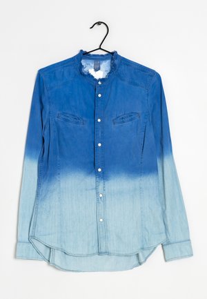 Camisa de mezclilla con un degradado que va de azul oscuro a azul claro, mangas largas, cierre con botones en la parte delantera y dos bolsillos en el pecho. Cuello deshilachado.