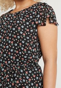 Czarna sukienka w kwiaty z krótkimi, falbaniastymi rękawami. Posiada kolorowe kwiaty w odcieniach czerwieni, niebieskiego i zieleni oraz słupek do wiązania w talii.