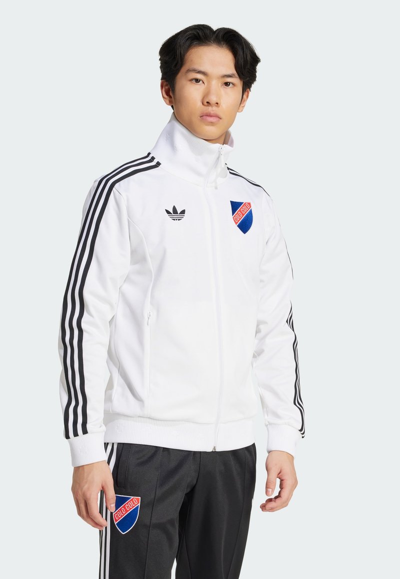 White zip-up athletic jacket made of smooth fabric, featuring black stripes along the sleeves and a blue and red logo on the chest.