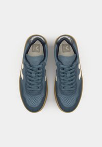 Sneakers in suede blu con punta perforata, dettagli bianchi, lacci piatti e suola in gomma color caramello. Presenta il logo sulla linguetta e sul lato.