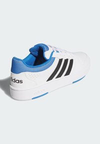 Bijele atletske tenisice s plavim naglascima, crnim prugama, teksturiranim materijalom, jastučićem oko gležnja i glatkim gumenim potplatom. Logo na peti.