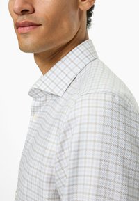 Leichtes kariertes Hemd aus Stoff mit dezentem Glanz in blassem Grau und Cremefarben, mit Knopfkragen und glatter Textur.