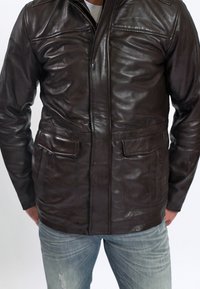 Braune Lederjacke mit einem Reißverschluss, zwei Fronttaschen und einer glatten Textur. Sie verfügt über Nähte an den Schultern und im Brustbereich.