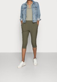 Jeansjacka, ljusblå; olivgröna cropade byxor med elastisk midja, framfickor; vita sneakers med subtila gröna accenter.