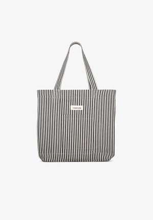 Sac cabas en tissu à rayures verticales noires et blanches avec deux poignées et une petite étiquette rectangulaire à l'avant.