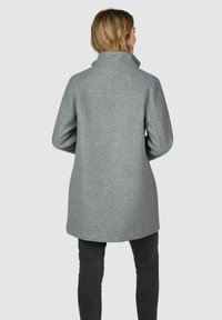 Hellgrauer Wollmischungs-Mantel mit hohem Kragen, A-Linie-Silhouette und strukturierten Schultern. Glatte Textur mit minimalen Nähten und ohne sichtbare Verschlüsse.