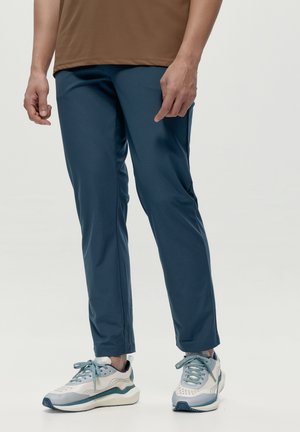 Blauwe sportbroeken met een gladde textuur, taps toelopend ontwerp en zijnaad. Draag de broek met lichtgrijze sneakers met blauwe accenten.