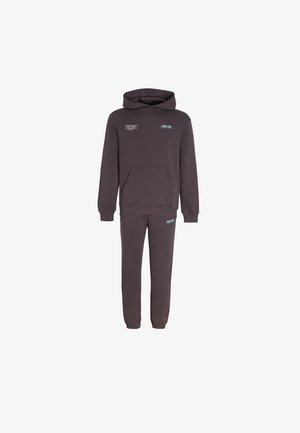 Tumehall kapuutsiga pusa ja sobivad dressipüksid, millel on väiksed valged ja sinakasrohelised tekstilogod rinnal ja reiel.