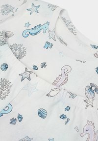 Bílé loungewear z měkké látky s námořními motivy, které obsahují modré a fialové mořské koníky, mušle a hvězdice, s elastickým pasem.