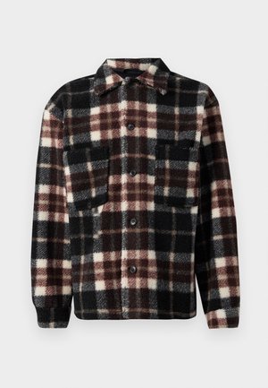 Veste en flanelle à carreaux noirs, blancs et marron, avec un col, une fermeture à boutons et deux poches poitrine. Tissu doux et texturé.