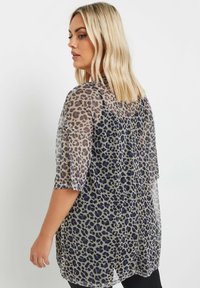 Gennemsigtig, let bluse med et grå- og sort leopardprint med blå accenter, korte ærmer og en afslappet pasform.