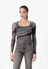 Top cu mâneci lungi, ajustat, din plasă gri transparentă, cu decolteu pătrat și un model spiralat; asortat cu blugi gri cu talie înaltă.