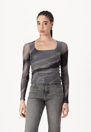 Long-sleeve, fitted top in sheer gray mesh with a square neckline and swirling pattern; paired with high-waisted gray jeans.