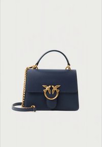 Tmavě modrá kožená kabelka s horním držadlem, zlatým řetízkovým popruhem a zlatou sponou ve tvaru ptáka na přední klopě.