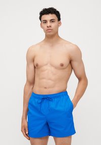Blauwe zwemboxers van lichtgewicht materiaal, voorzien van een elastische tailleband met een trekkoord en zijzakken. Soepele textuur, effen kleur.