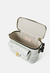 Hvit sprukket skinnveske med svart glidelås og gull hardware. Har en klafflomme og et uforet interiør med et merke. 