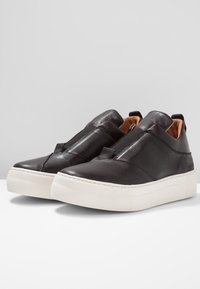 Svarta läder slip-on sneakers med en vit gummi sula, elastiska sidopaneler och en mjuk yta. Har en minimalistisk design och sömnad.