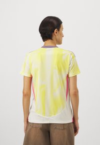 Kortärmad mesh-tröja med gula, vita och rosa färger, rund hals och ventilerad textur bak och på sidorna.