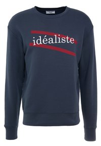 Sudadera azul marino de manga larga con el texto rojo y blanco "idéaliste" en la parte delantera, sobre un fondo de textura de tela suave.