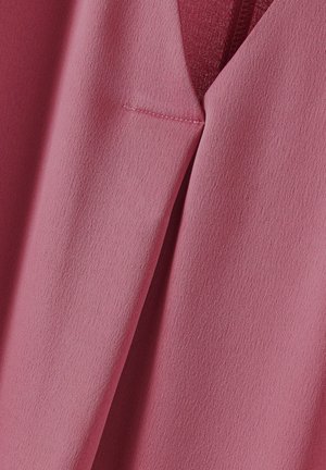 Rosa stof med en glat tekstur, der har et skræddersyet design og diskret syning. Inkluderer en lille, diskret lomme.